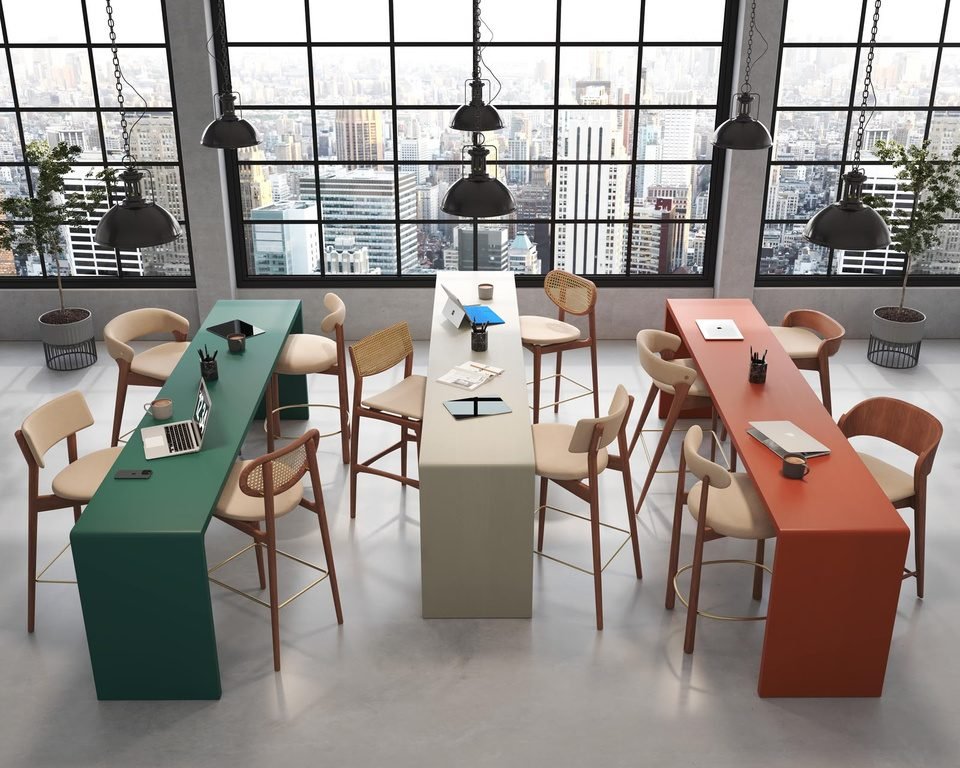 Coworking com mesas altas coloridas e banquetas de madeira