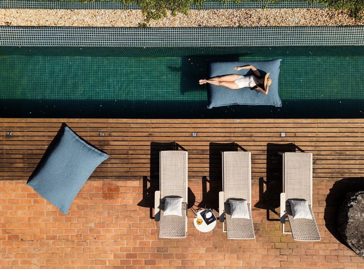 Espreguiçadeiras em deck de madeira ao lado da piscina de um resort